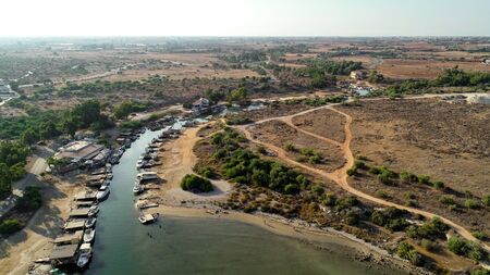 Aerial bird's eye view of Liopetri river to the sea (potamos Liopetriou), Famagusta, Cyprus. A landmark tourist attraction fishing village, natural fjord with colourful boats moored on the banks at Kokkinochoria, Ammochostos, from above.の写真素材