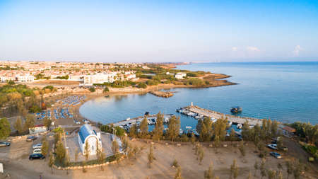 Aerial view of coastline sunset and landmark white washed chapel at Agia Triada beach, Protaras, Famagusta, Cyprus from above. Bird's eye view of tourist attraction Ayia Trias bay church, sand, port at sunrise in Ammochostos district.の写真素材