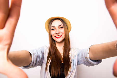 Portrait of a smiling cute woman making selfie photo from hands isolated on a white backgroundの写真素材