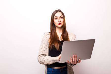 Happy young woman holding laptop and looking at camera over white backgroundの写真素材