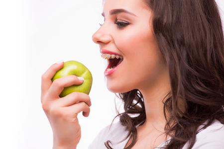 Young girl with brances eat apple. Female teeth with dental braces and apple. Healthy eating with bracesの写真素材