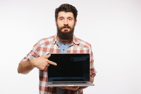 Portrait of handsome hipster bearded man with laptop. Bearded Man demonstrating laptop against white backgroundの写真素材