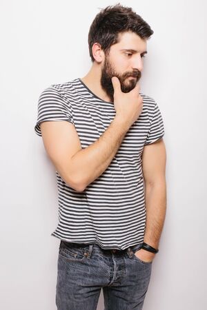 Side Portrait handsome young man with  hand on beard smiling while standing against white backgroundの写真素材