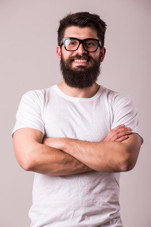 Bearded man in glasses with crossed hands look at camera on whiteの写真素材