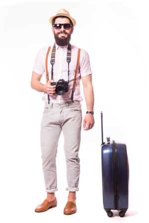 Young creative tourist man is posing with suitcase on grey background.の写真素材