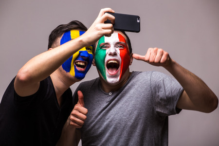 Italy vs Sweden football fans take selfie photo with phone on grey background. European football fans concept.の写真素材