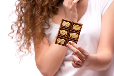 Close up curly woman eat a piece of chocolate and pointed second