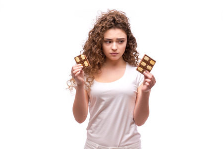 Portrait of curly young woman eating a chocolate bar against a white backgroundの写真素材