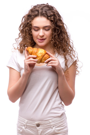 Curly woman eating a croissant on isolated backgroundの写真素材