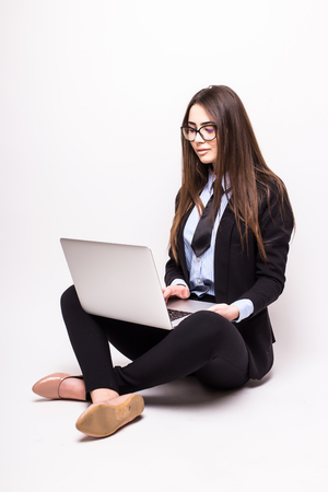 young woman working on her laptop, sitting on the floor over sparse white backgroundの写真素材
