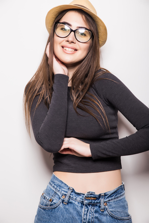 Portrait of beautiful young woman in glasses and funky hat over white backgroundの写真素材