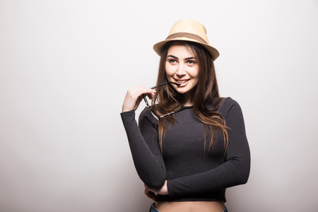 Portrait of beautiful young woman in glasses and funky hat over white backgroundの写真素材