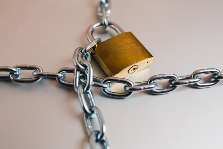 Heavy with a padlock around a laptop isolated on grey table.の写真素材