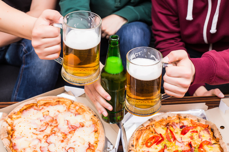 Close up of home fans eating: pizza and beerの写真素材