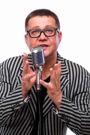 Portrait of middle age showman singing in microphone with emotional gesture