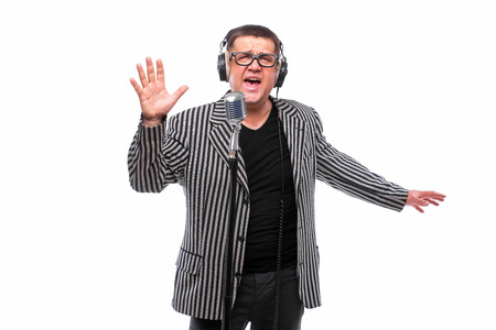 Showman concept. Singer listening music and sing in microphone on white backgroundの写真素材