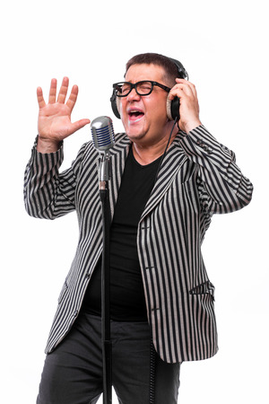 Showman concept. Singer listening music and sing in microphone on white backgroundの写真素材