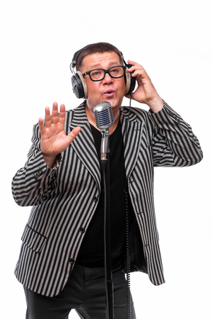 Showman concept. Singer listening music and sing in microphone on white backgroundの写真素材