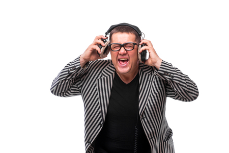 Showman concept. Middle age man listen music on headphones and sing song on whiteの写真素材