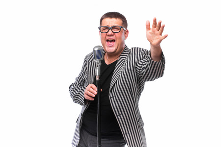 Portrait of middle age showman singing in microphone with emotional gestureの写真素材