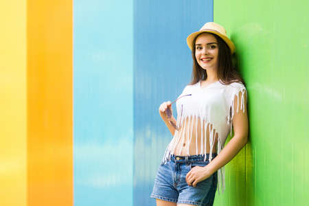 Outside portrait of pretty woman  in sunglasses and hat over color backgroundの写真素材