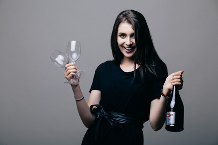 Beauty girl with champagne bottle and drink glass on grey background.の写真素材