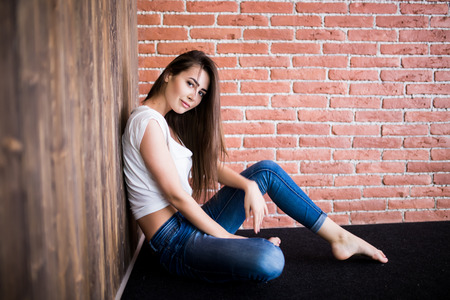 Girl sitting down against wooden and brick wallの写真素材