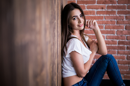 Girl sitting down against wooden and brick wallの写真素材