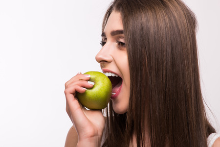 Young girl  eat apple. Female teeth  and apple. Healthy eating on white backgroundの写真素材