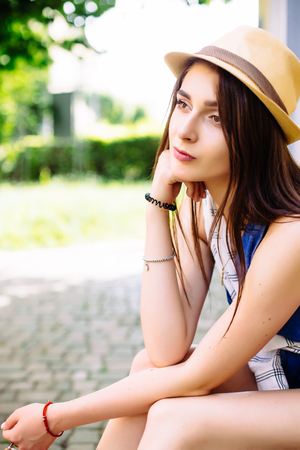 portrait of pretty young sitting girl, wearing in hat and sunglasses on urban background.の写真素材