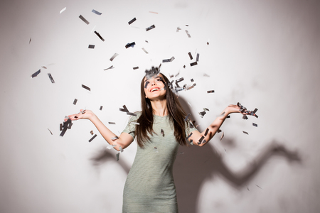 happy young woman or teen girl in fancy dress with sequins and confetti at party on grey backgroundの写真素材