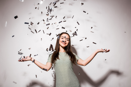 happy young woman or teen girl in fancy dress with sequins and confetti at party on grey backgroundの写真素材