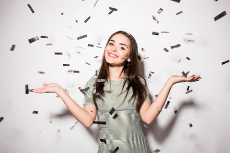 happy young woman or teen girl in fancy dress with sequins and confetti at party on grey background