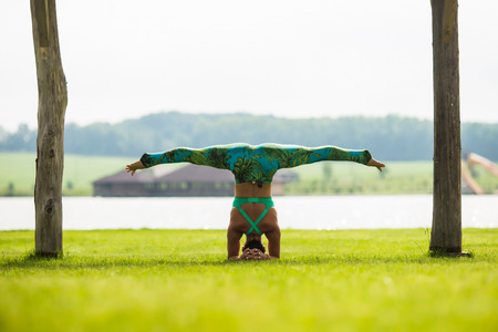 shirshasana. Yoga girl training outdoors on nature background. Yoga concept.