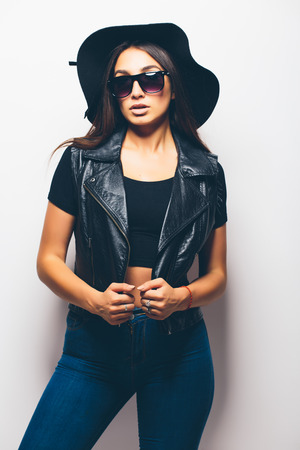 beautiful fashion mulatto girl wearing sunglasses and black hat over a white background.の写真素材