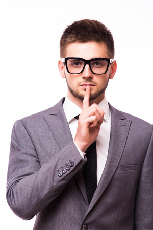 Businessman pointing finger over lips, asking for silence over gray background.の写真素材