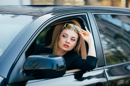 Girl in sunglasses drive a car and look from windowの写真素材
