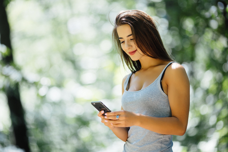 A portrait of a smiling beautiful woman texting with her phoneの写真素材
