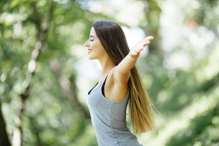 Carefree and free cheering woman in the park. girl raising her arms up smiling happyの写真素材