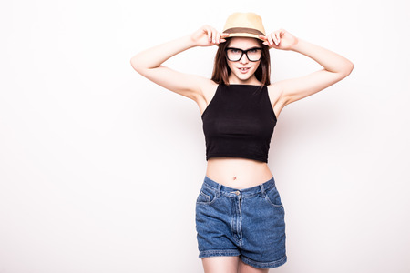 young attractive girl taking selfie photo portrait with mobile phone or camera wearing sunglasses hat and summer dress in chic trendy tourist look smiling happy isolated on white backgroundの写真素材