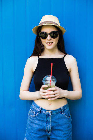 Girl drink lemonade on blue backgroundの写真素材