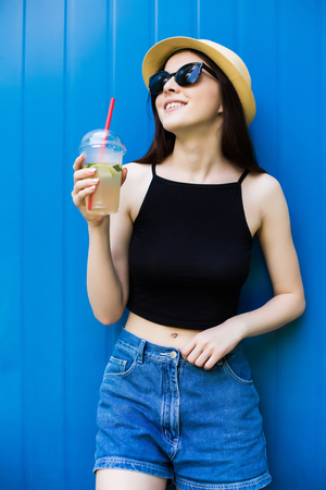 Girl drink lemonade on blue backgroundの写真素材