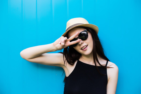 young woman wearing sunglasses in jeans on blue backgroundの写真素材