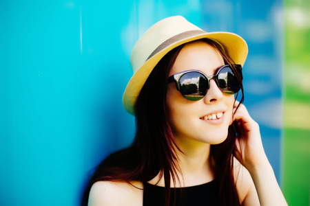 Smiling summer woman with hat and sunglasses over bright background.の写真素材