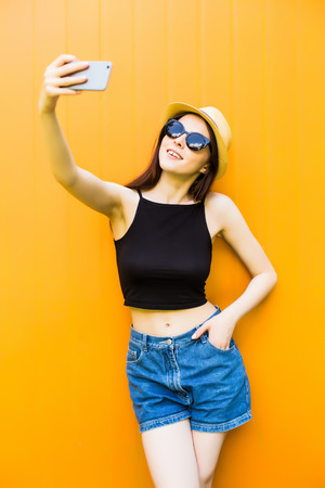 Smiling summer woman take selfie with hat and sunglasses over bright background.の写真素材