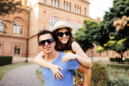 Happy young man piggybacking his girlfriend while keeping arms outstretchedの写真素材