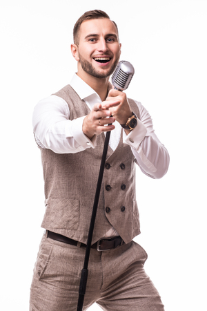 Portrait young showman in suit singing with emotions gesture over the microphone with energy. Isolated on white background. Singer concept.の写真素材