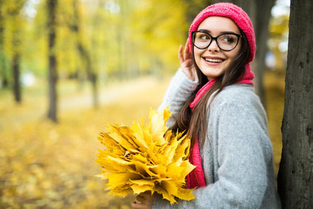 Student girl with maple leaves in hands in autumn park