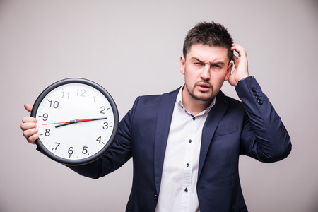 Handsome man in suit with clock in hand lose time of meeting