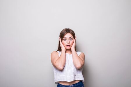 Girl close ears with hands on a gray background